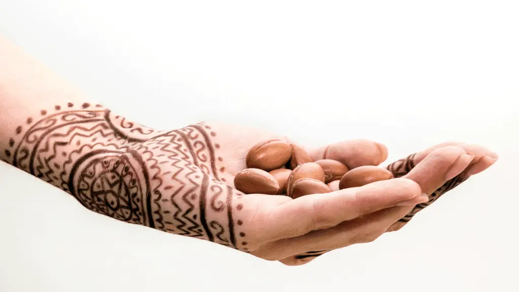 Una mano decorada con henna sujetando frutos de argán