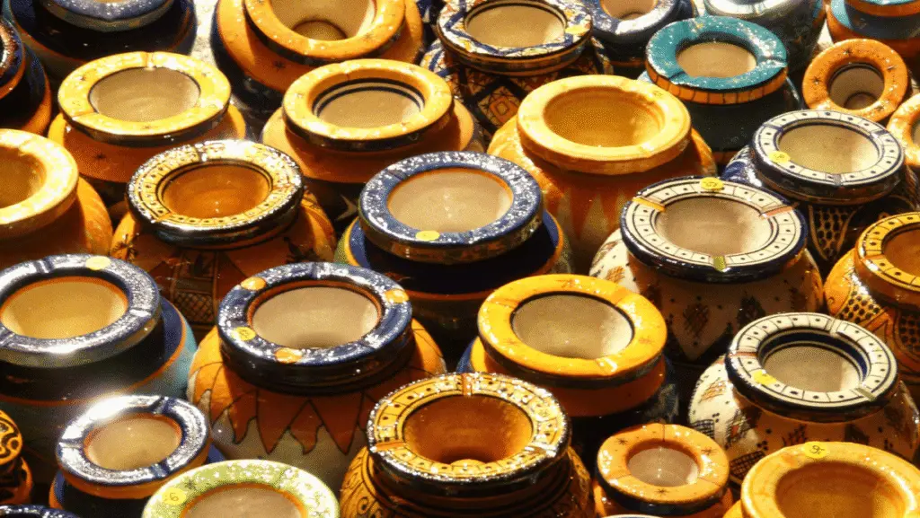 Filas de vasijas marroquíes esmaltadas con bordes pintados a mano en azul, amarillo y verde