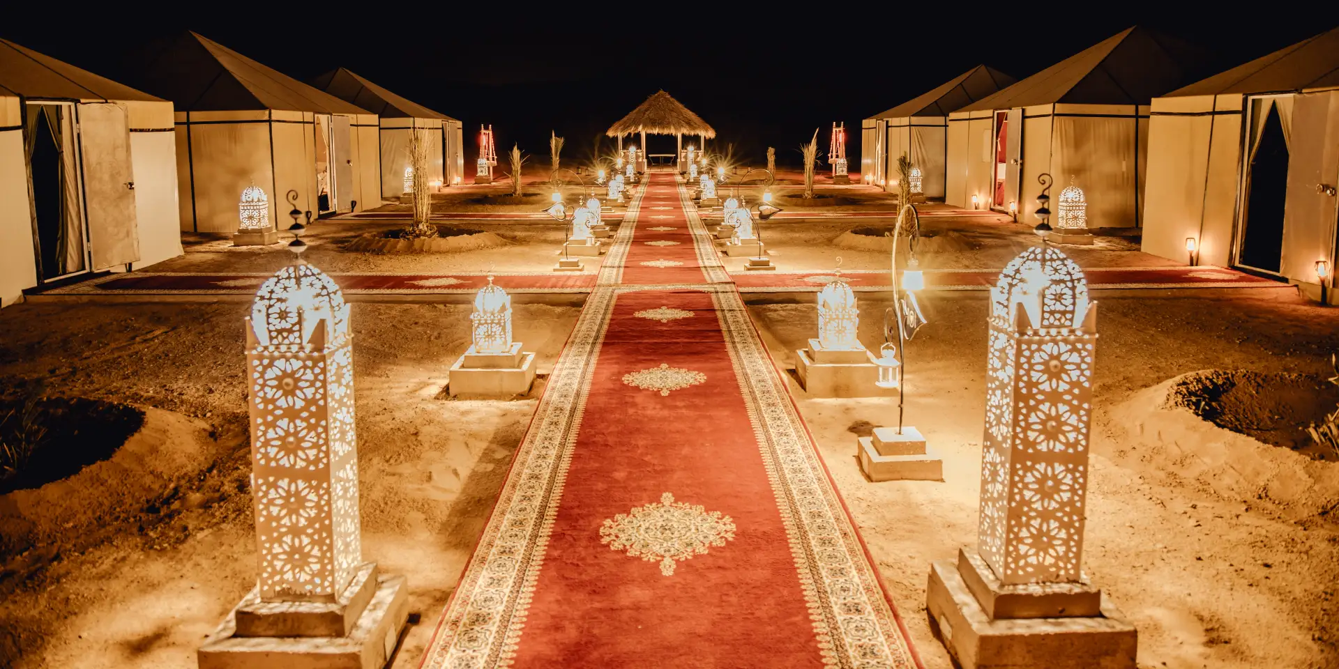 Campamento de Feliz Viaje a Marruecos iluminado de noche en el desierto